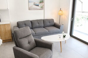 Un salon moderne avec un canapé gris, un fauteuil assorti, une table basse blanche et un lampadaire.