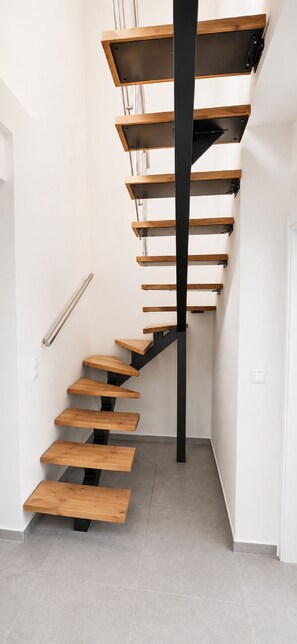 A spiral staircase with wooden steps and black metal railings. - Zidros Apartments Maisonette Apartment 4 (Sfakaki)