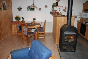 Ein gemütliches Wohnzimmer mit einer Couch, einem Holzesstisch, Stühlen und einem Kaminofen.