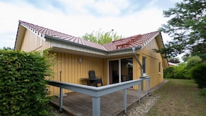 A single-story wooden house with a porch, a small deck, and a covered outdoor seating area. - Praktischer Doppelbungalow mit Terrasse im Ferienpark Mirow (Mirow)