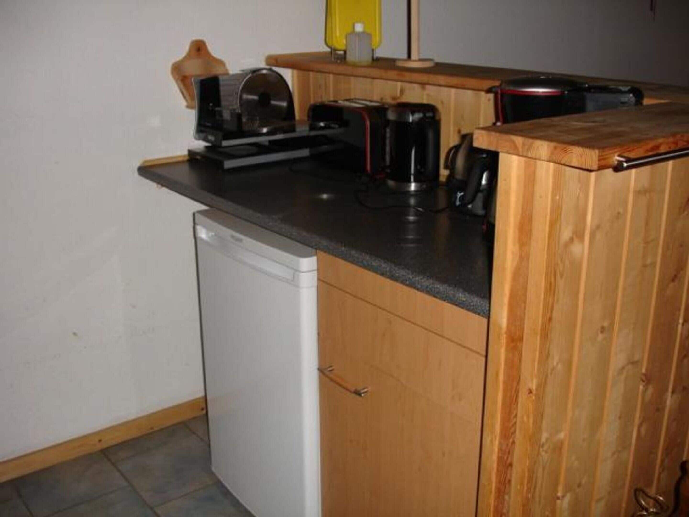 A compact kitchen with a dishwasher, a coffee maker, and a toaster on the countertop.