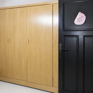 Un armario de madera con una puerta negra y un pequeño letrero rosa.