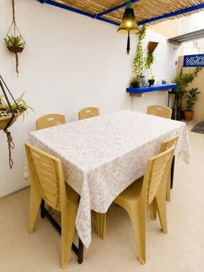 Un comedor con una mesa cubierta con un mantel floral, rodeada por cuatro sillas.