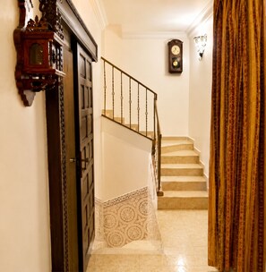 A staircase with a patterned carpet, a wooden door, and a wall-mounted clock.