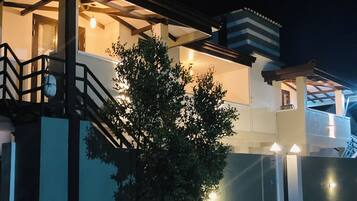 A two-story building with a balcony, a staircase, and a small tree in front.