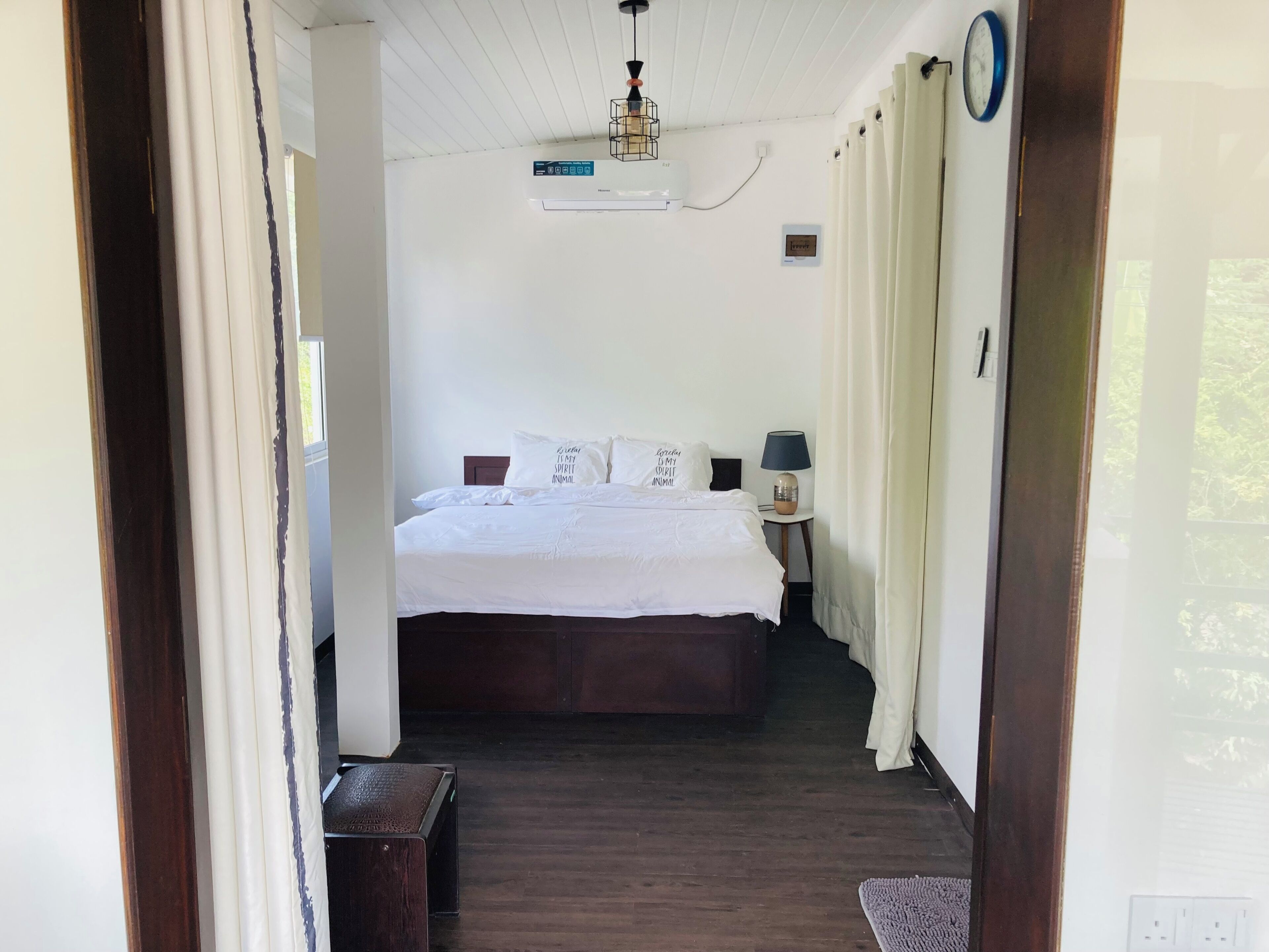 Une chambre à coucher comprenant un lit, une table de chevet, une lampe et un appareil de climatisation.