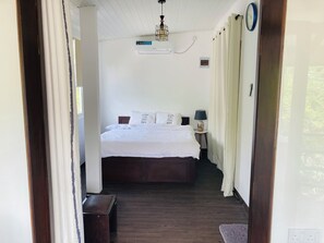 Une chambre à coucher comprenant un lit, une table de chevet, une lampe et un appareil de climatisation.