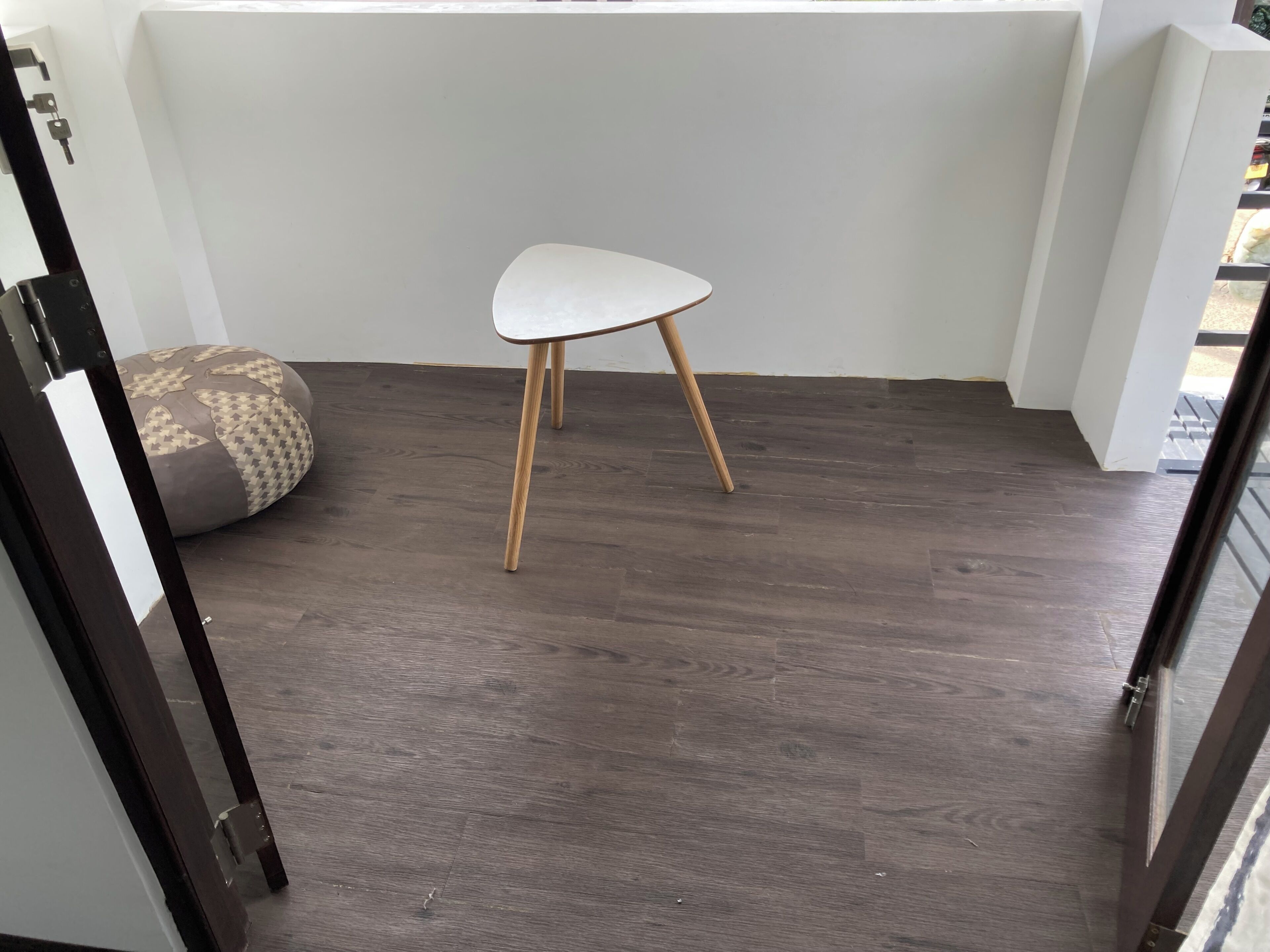 Una stanza con pavimento in legno, una sedia bianca e un cuscino decorato.