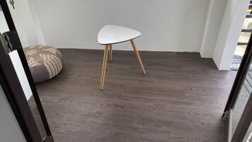 Une pièce avec un plancher en bois, une chaise blanche et un coussin à motifs.