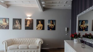 A room with a white sofa, a white cabinet, and a wall with five paintings. - Fornarina a Trastevere by Welcome In (Rome)
