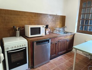 Eine kleine Küche mit Mikrowelle, Herd, Geschirrspüler und Holzschränken.