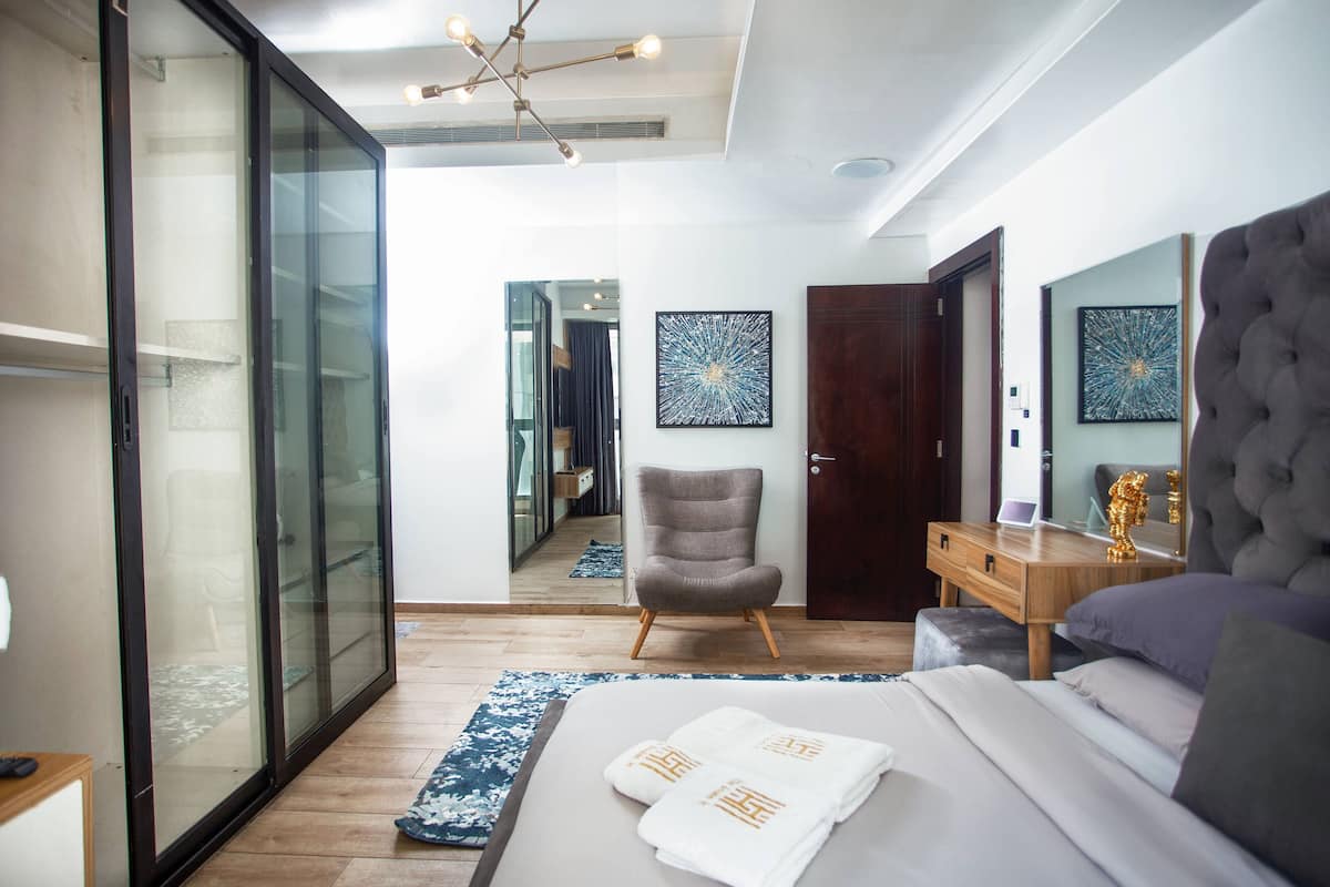 Une chambre à coucher moderne avec un lit, une chaise, un bureau et un grand miroir.