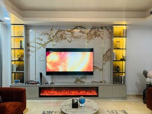 Una sala de estar moderna con televisor de pantalla plana, chimenea y paneles de pared de mármol.