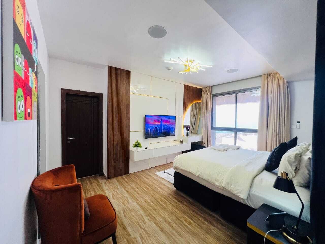 A modern hotel room with a bed, TV, and a desk with a chair.