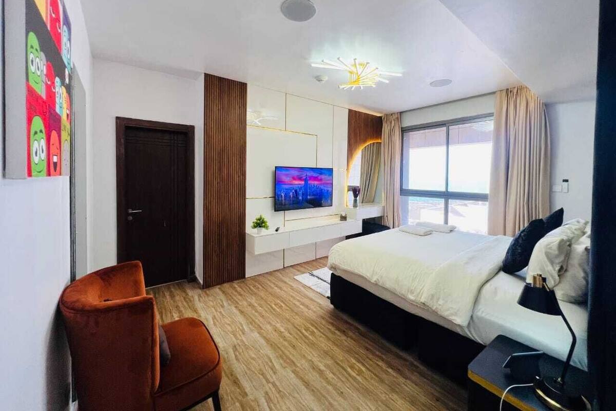 Une chambre d’hôtel moderne équipée d’un lit, d’une télévision et d’un bureau avec une chaise.