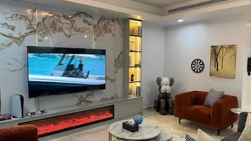 A modern living room with a flat-screen TV, a fireplace, and a cozy seating area.