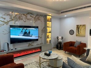 Una sala de estar moderna con un televisor de pantalla plana, una chimenea y un área de estar acogedora.
