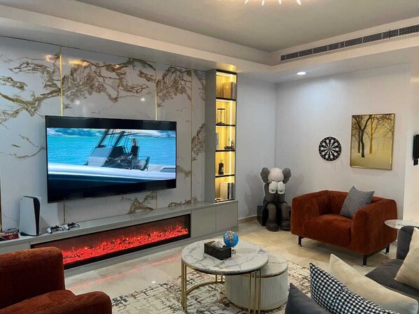 A modern living room with a flat-screen TV, a fireplace, and a cozy seating area.