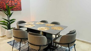 A dining area with a table, chairs, and a potted plant. - Eko Atlantic Apartment (Lagos)