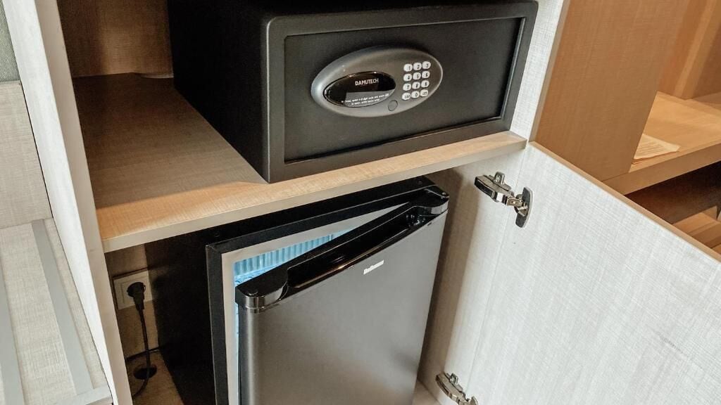 A compact kitchen with a built-in refrigerator, a microwave, and a secure storage unit.