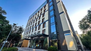 Un moderno edificio de hotel con fachada de vidrio, una entrada destacada y un letrero que indica que es un hotel urbano.