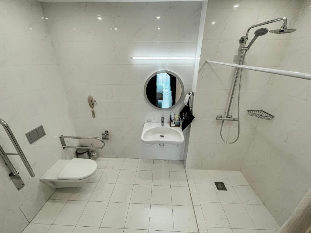 A small, modern bathroom with a toilet, sink, and shower.