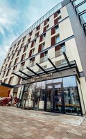 A modern hotel with a glass facade, a prominent entrance, and a clear sky.