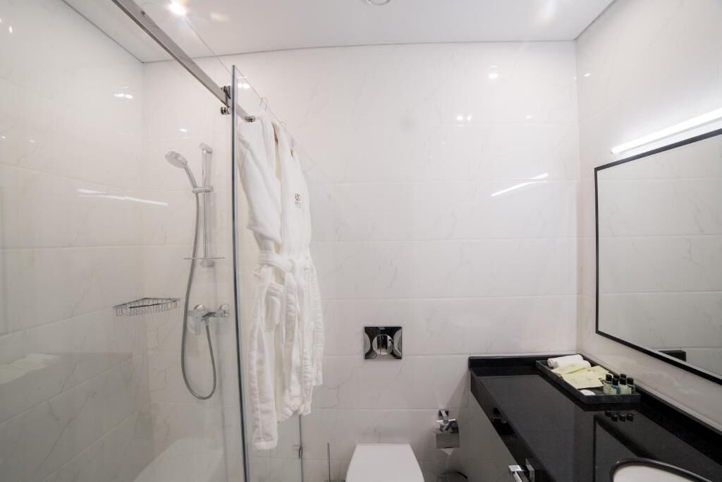 Un baño moderno con cabina de ducha de vidrio, un lavamanos negro y un espejo grande.