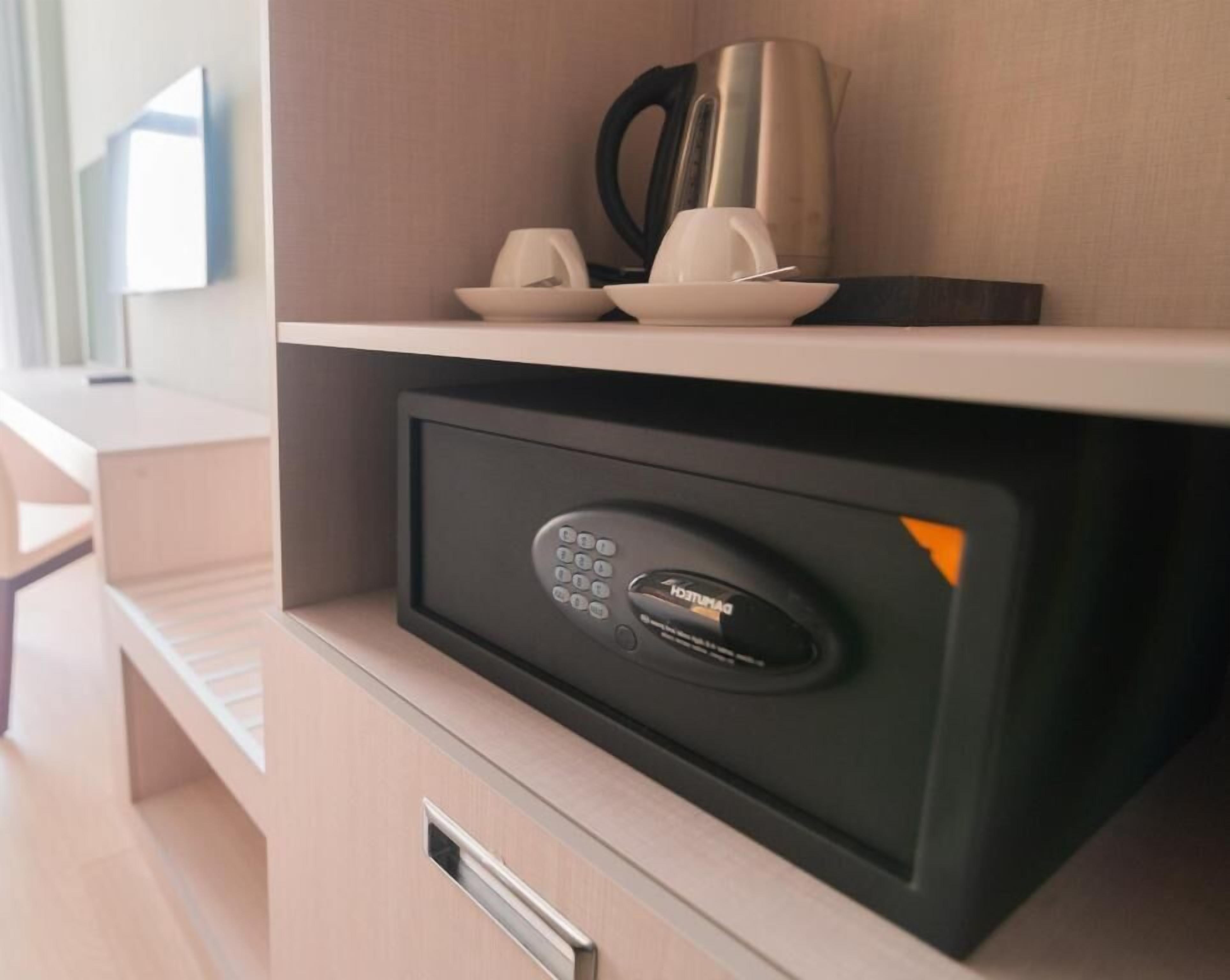 Un compartimento de almacenamiento seguro con cerradura electrónica, una cafetera y una taza sobre una estantería.
