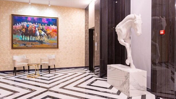 A lobby with a geometric patterned floor, a large abstract painting, a white horse sculpture, and two white chairs. - Resident City Hotel (Almaty)