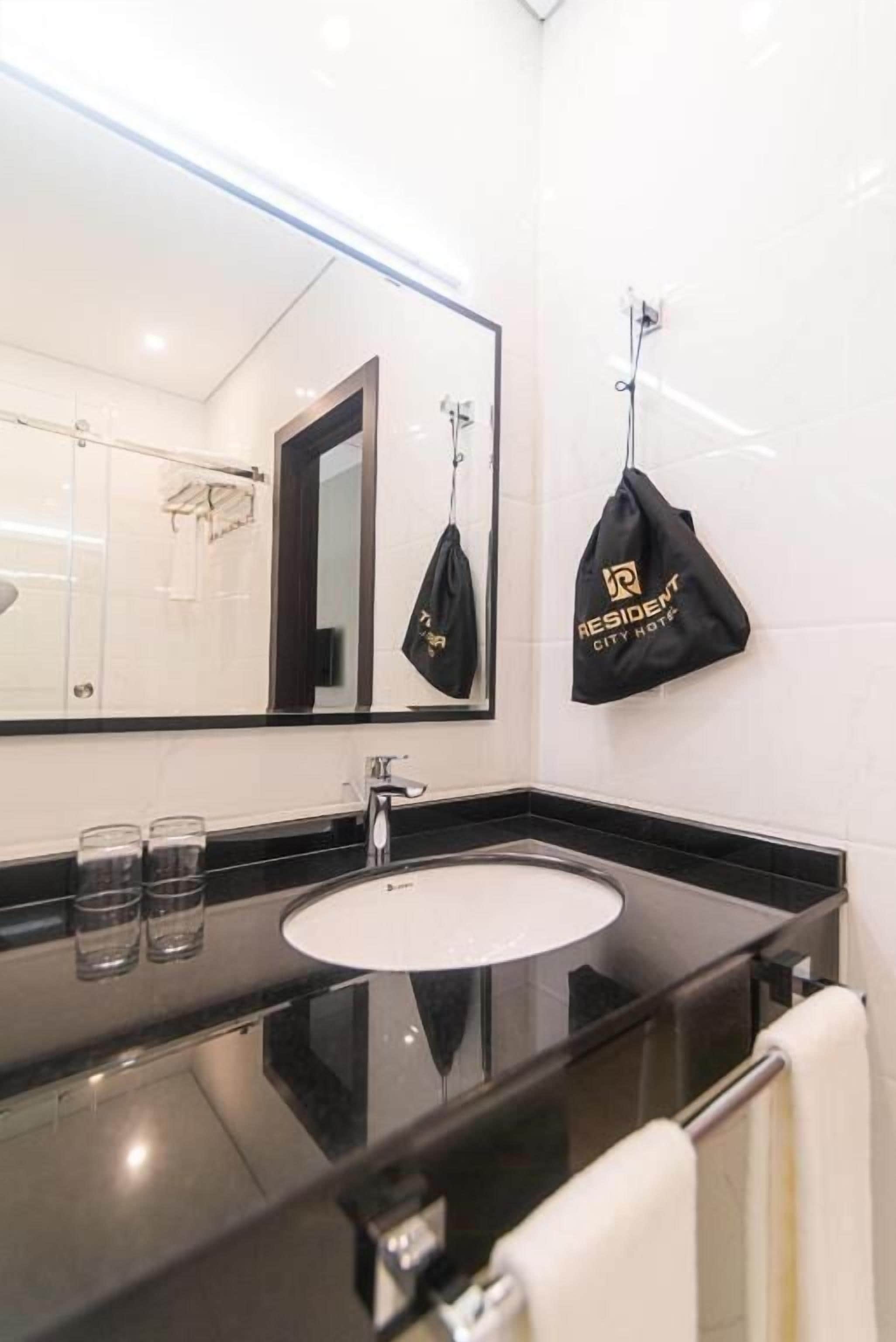 Un baño moderno con encimera negra, lavabo blanco y un espejo grande.