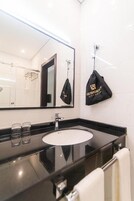 Un baño moderno con encimera negra, lavabo blanco y un espejo grande.
