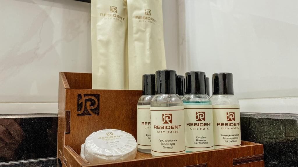 A wooden box containing a bar of soap, a bottle of shower gel, and three bottles of hair products.