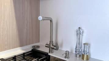 Una cocina con un lavamanos de acero inoxidable, un grifo y un escurreplatos.