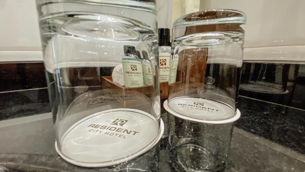 Eine Hotelminibar mit klaren Glasbehältern, die jeweils mit dem Namen des Hotels beschriftet sind.