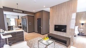A modern living room with a flat-screen TV, a fireplace, and a dining area with a glass table. - Resident City Hotel (Almaty)