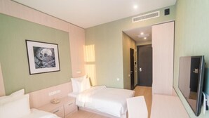 A hotel room with two beds, a desk, a chair, a TV, and a framed picture on the wall. - Resident City Hotel (Almaty)