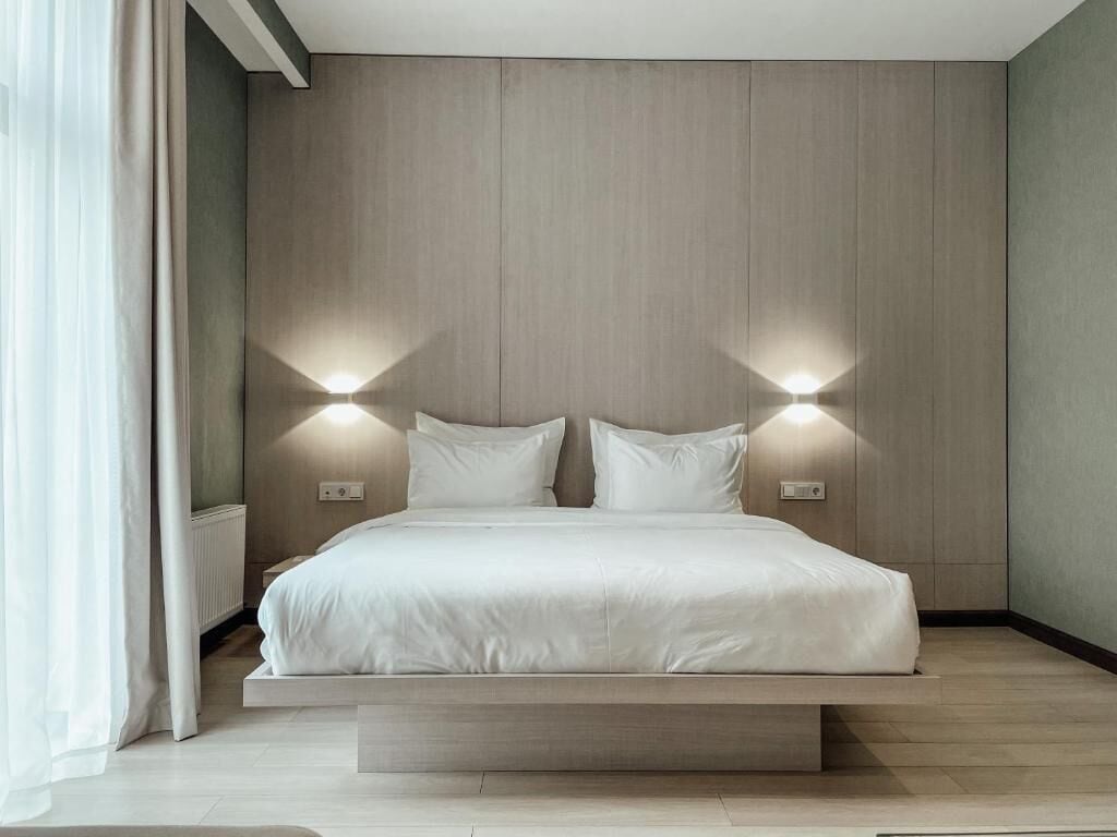 A modern bedroom with a bed, two wall-mounted lights, and a built-in bench.