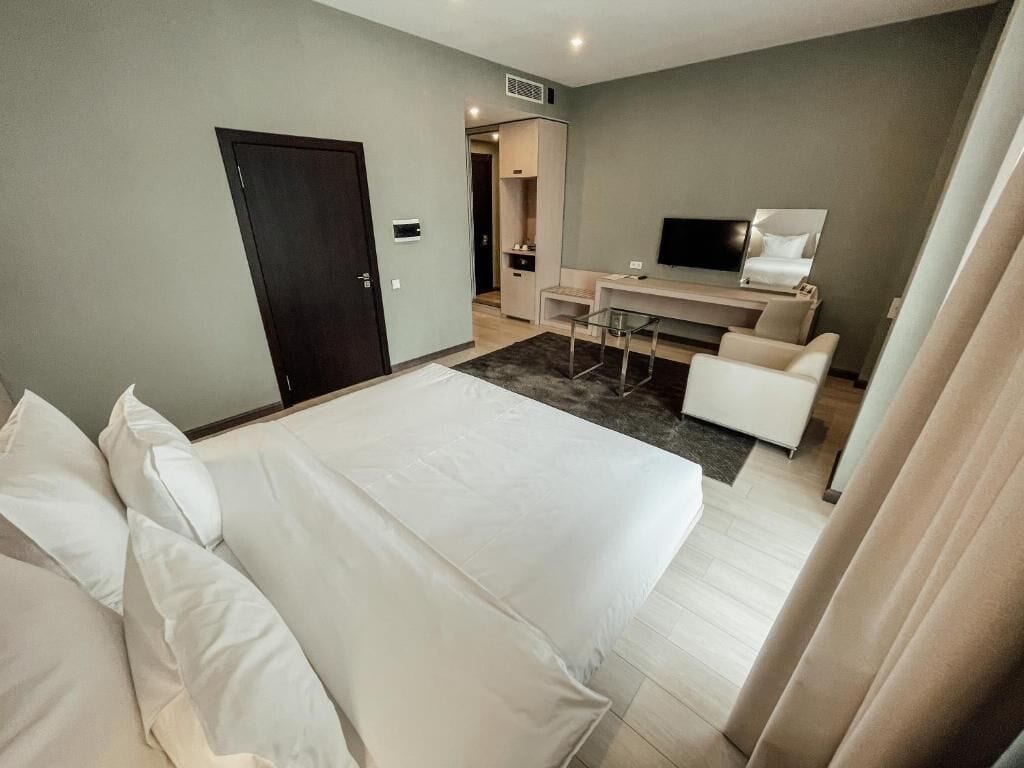 Una habitación de hotel con cama, escritorio, silla y televisión.