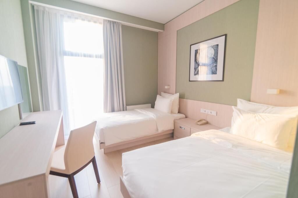 A hotel room with two beds, a desk, and a chair.