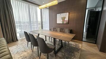 Un comedor moderno con una mesa rectangular, cuatro sillas, un tapete estampado y una lámpara colgante.