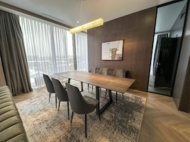 Un comedor moderno con una mesa rectangular, cuatro sillas, un tapete estampado y una lámpara colgante.