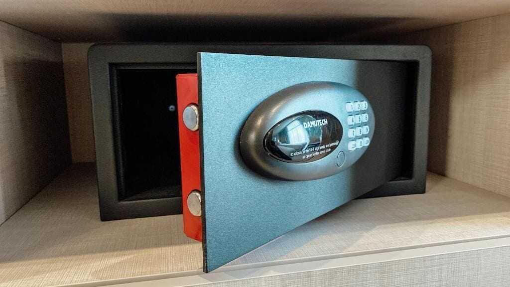 A safe with a blue door and a keyhole, placed inside a wooden cabinet.
