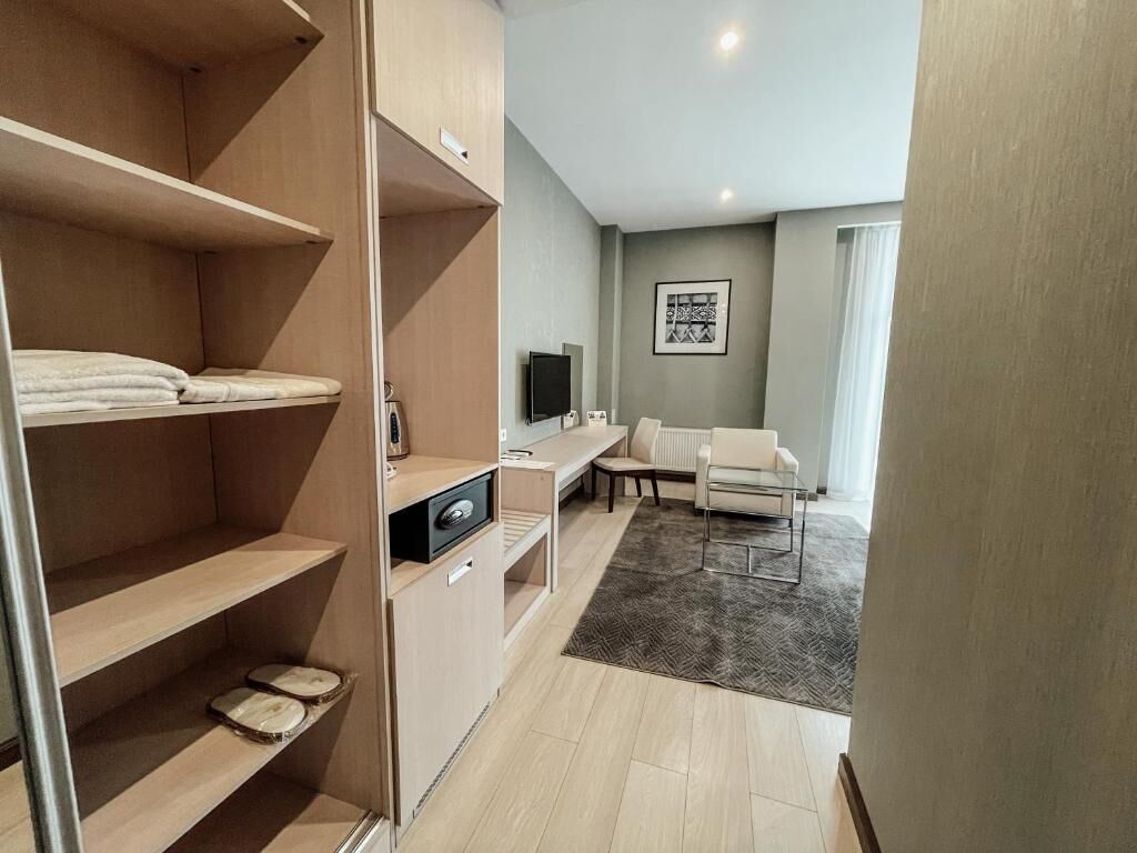 A modern hotel room with a bed, a desk, a television, and a sofa.