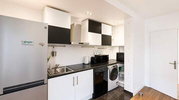 Una cocina moderna con refrigerador, microondas, tostadora y lavadora.