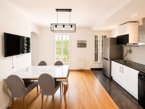 Een moderne keuken met een eethoek, een flatscreen tv aan de muur en een groot raam voor natuurlijk licht.