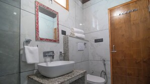 Un baño con lavamanos blanco, un espejo con marco rojo, una puerta de madera y una ducha.