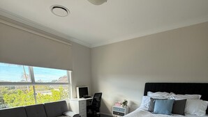 Ein Schlafzimmer mit Bett, Sofa, Schreibtisch und Fenster mit Blick.