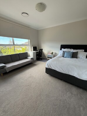 Ein Schlafzimmer mit Bett, Sofa, Schreibtisch und Fenster mit Blick.