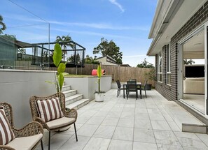 Un patio con mobiliario exterior, un cerramiento de vidrio y una valla de madera.